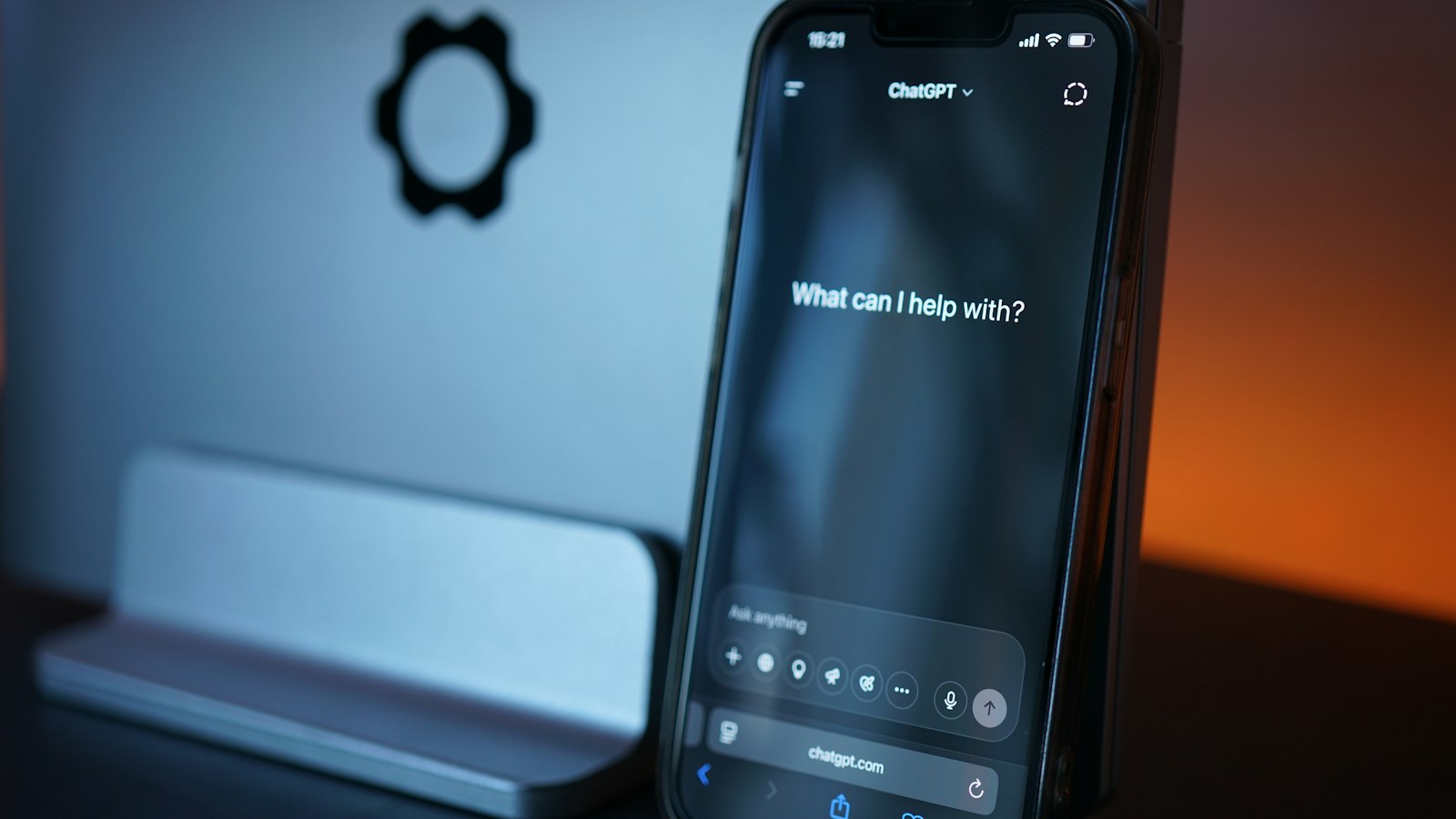 Smartphone posé devant un écran, ouvert sur la page d'accueil de ChatGPT